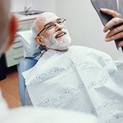 Man at dentist smiling at handheld mirror