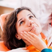 Woman with toothache looking at emergency dentist
