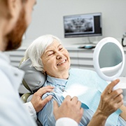 An older woman admiring her new dental implants