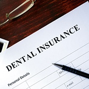Closeup of dental insurance paper, x-ray, and money on desk