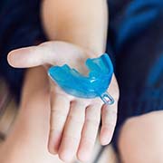 Outstretched hand holding mouthguard for preventing dental emergencies in Pepper Pike