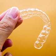 Closeup of Invisalign clear aligner with yellow background
