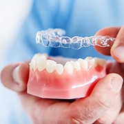Invisalign dentist in Pepper Pike putting clear aligner on model of teeth