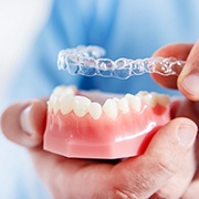 Invisalign dentist in Pepper Pike putting clear aligner on model of teeth