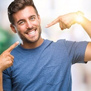 young man pointing to his smile after getting teeth whitening in Pepper Pike 