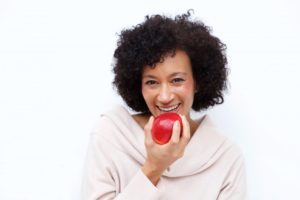 woman with dental implants in Pepper Pike eating red apple
