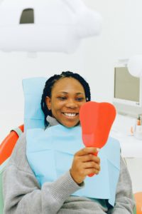 Woman looking in dental mirror smiling