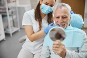 Older man smiling after receiving dental implants.